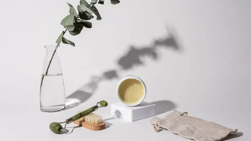 Pot de soin, brosse et branche d'eucalyptus sur fond clair