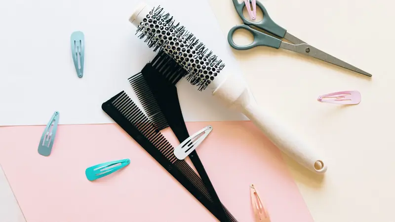 Brosse ronde, peignes et pinces à cheveux sur un fond clair