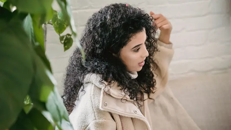 Femme aux longs cheveux bouclés noirs qui ajuste ses boucles