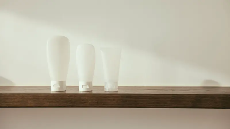 Flacons blancs de produits de toilette alignés sur une étagère