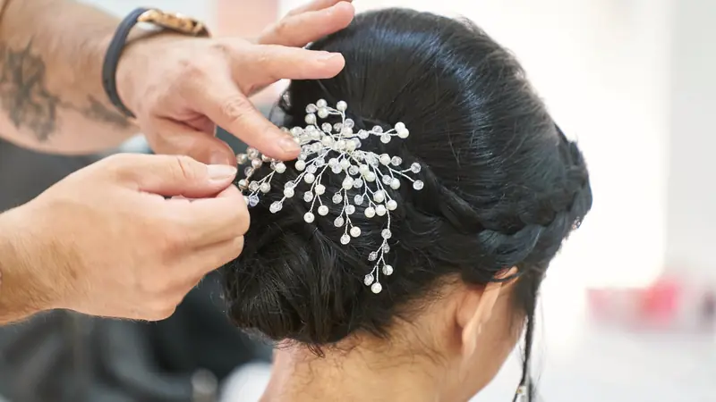 Coiffeur qui fixe un bijou de cheveux dans un chignon