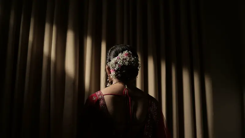 Mariée de dos avec un chignon orné de fleurs, dans la pénombre