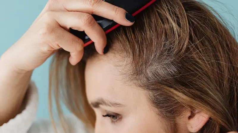 Femme qui écarte ses cheveux pour observer ses racines