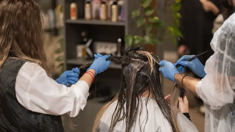 Deux coloristes qui appliquent une couleur au pinceau en salon