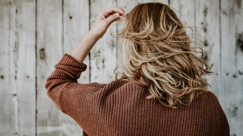 Femme de dos aux cheveux ondulés méchés de blond