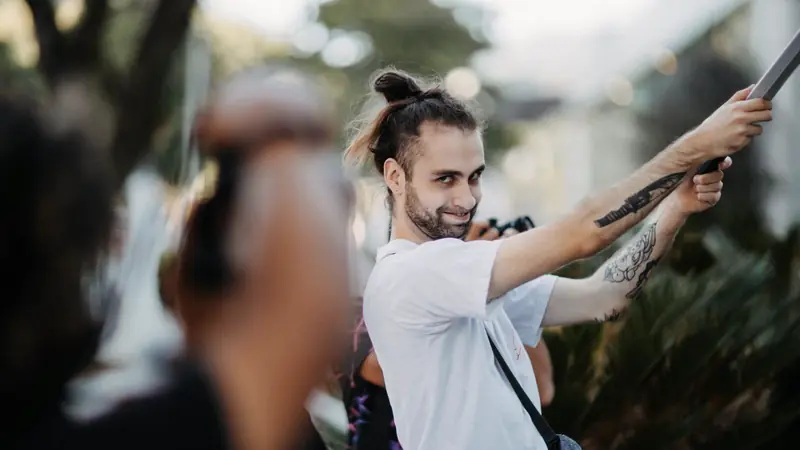 Homme barbu aux cheveux longs attachés en chignon haut, en plein air