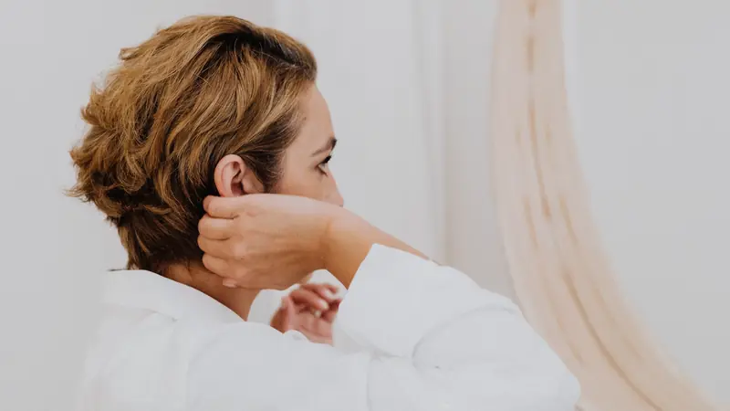 Femme aux cheveux courts ondulés qui se coiffe avec les doigts