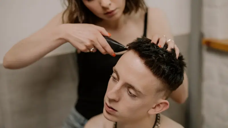Coiffeuse qui travaille une coupe courte à la tondeuse