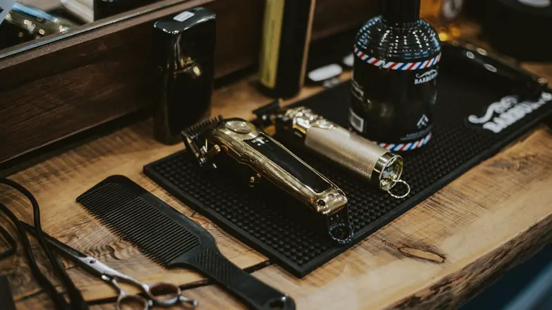 Tondeuses, peigne et ciseaux posés sur un tapis de travail en caoutchouc, sur le plan en bois d'un barbier