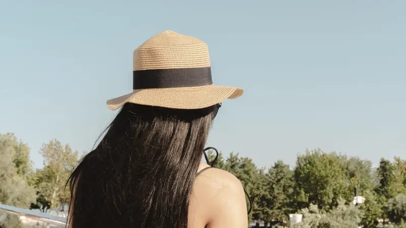Femme aux longs cheveux bruns coiffée d'un chapeau de paille