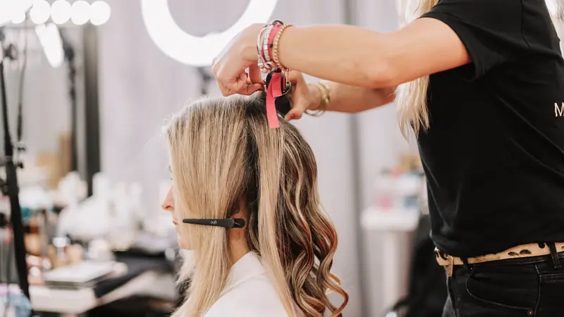 Coiffeuse qui pose des extensions de cheveux en salon