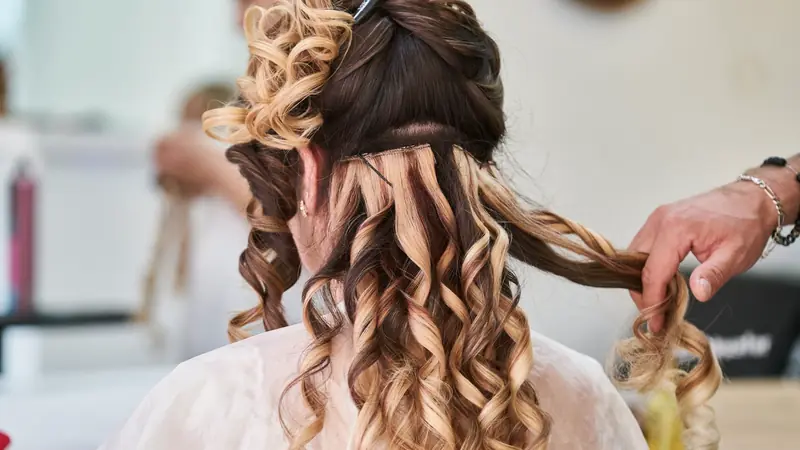 Coiffeur qui pose des mèches d'extensions ondulées