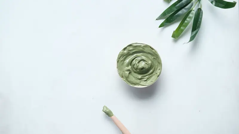 Coupelle d'argile verte et pinceau sur fond clair