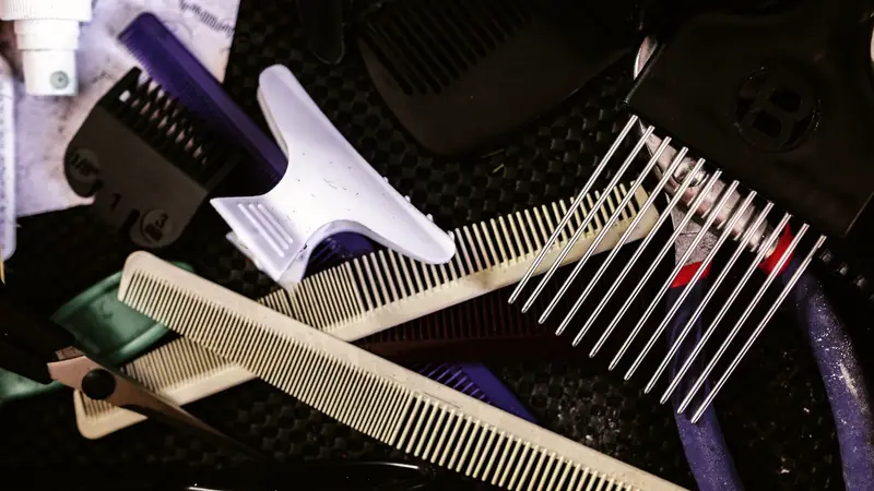 Peignes de coupe, pince à cheveux, ciseaux et sabot de tondeuse en vrac sur un plan de travail de salon